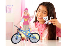 Girl holding a white cat figurine with a Barbie doll and bicycle in the background